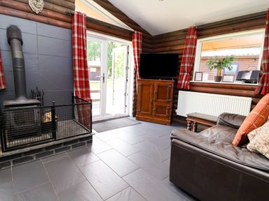A living room with a sofa and television at The Roe in Llanerch Park near St Asaph