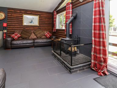A living room with a sofa and a fireplace at The Roe in Llanerch Park near St Asaph