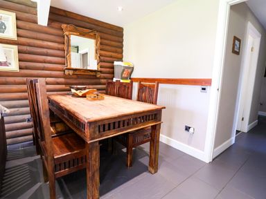 A dining room with a wooden table and chairs at The Roe in Llanerch Park near St Asaph