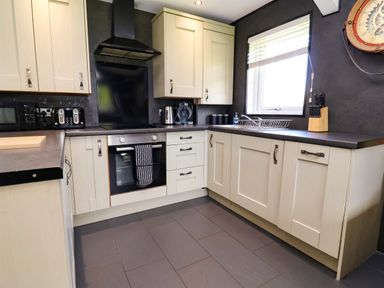 A kitchen with cabinets, oven, sink, and kettle at The Roe in Llanerch Park near St Asaph