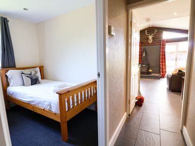 A bedroom with a bed and a doorway leading to a living area at The Roe in Llanerch Park near St Asaph