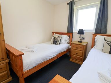 A bedroom with two single beds and a nightstand at The Roe in Llanerch Park near St Asaph