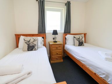 A bedroom with two single beds and a nightstand at The Roe in Llanerch Park near St Asaph