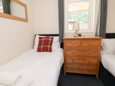 A bedroom with single beds and a wooden bedside table at The Roe Llanerch Park near St Asaph