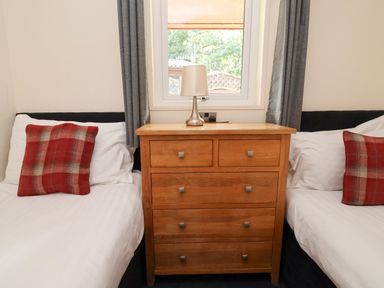 A bedroom with two beds and a wooden dresser at The Roe in Llanerch Park near St Asaph