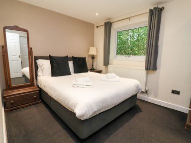 A bedroom with a bed, mirror and window at The Roe, Llanerch Park near St Asaph