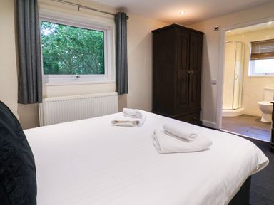 A bedroom with a bed and a wardrobe at The Roe in Llanerch Park near St Asaph