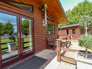 An outdoor area with wooden structures and bench at The Roe in Llanerch Park near St Asaph