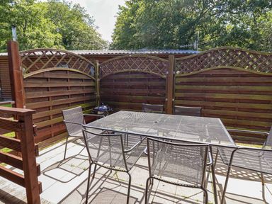 A garden with a table and chairs along a wooden fence at The Roe, Llanerch Park near St Asaph