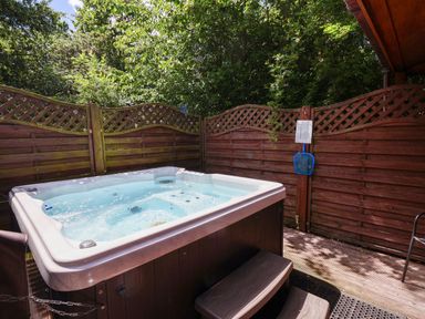 A hot tub surrounded by wooden fencing at The Roe in Llanerch Park near St Asaph
