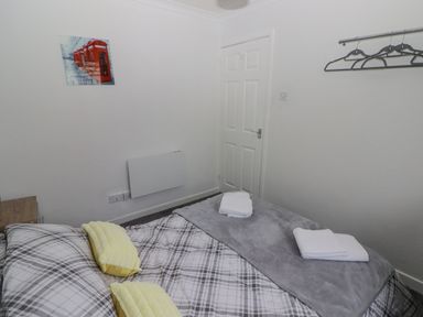 A bedroom with a bed covered in plaid bedding and yellow pillows with folded towels on a gray blanket at 48 Gower Holiday Village in Scurlage