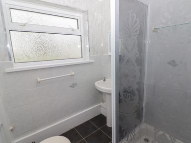 A bathroom with a frosted window a towel rail a pedestal sink and a glass shower cubicle at 48 Gower Holiday Village in Scurlage