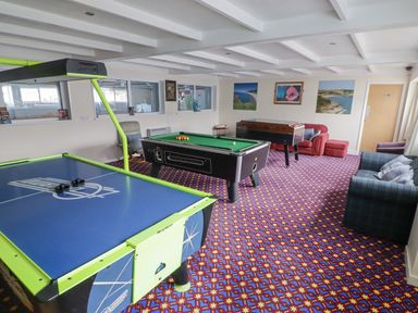 A game room with a table tennis table pool table foosball table and sofas at 48 Gower Holiday Village in Scurlage