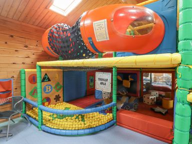 An indoor play area with a ball pit, slide tube, and toddler area with toys at 48 Gower Holiday Village in Scurlage