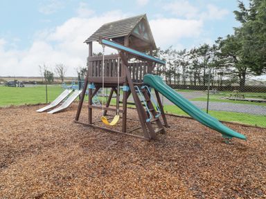 An outdoor playground with slides swings and climbing equipment at 48 Gower Holiday Village in Scurlage