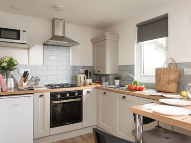 A kitchen with a gas stove oven microwave sink and dining area at Bushwood Lodge in Wendron near Helston