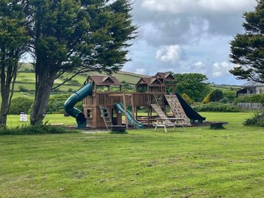 An outdoor playground with slides and climbing features in a grassy area at Bushwood Lodge in Wendron near Helston