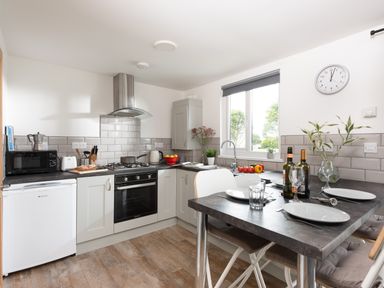 A kitchen with appliances and a dining table set for four at Wheal Jewel Lodge in Wendron near Helston