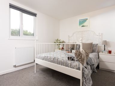 A bedroom with a white metal bed frame and bedside tables at Wheal Prosper Lodge Wendron near Helston
