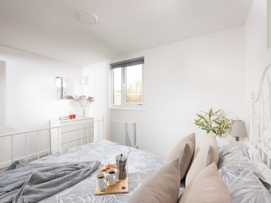 A bedroom with a bed a tray with coffee cups and snacks a dresser with flowers and a window at Wheal Prosper Lodge in Wendron near Helston