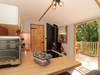 A kitchen with wooden countertops a microwave stove and a door leading to a wooden deck at The Foxes Den Shepherds Hut Oldbury-On-Severn