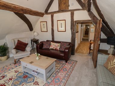 A sitting room with armchairs sofas a coffee table and wooden beams at The Bindery in Broadway