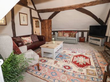 A living room with sofas armchair coffee table television and a patterned rug at The Bindery in Broadway