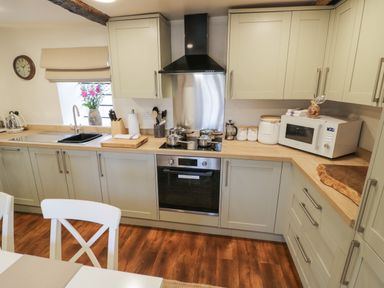 A kitchen with wooden countertops gray cabinets a sink stove oven microwave and wooden floor at The Bindery in Broadway