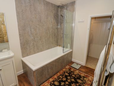 A bathroom with a bathtub shower combination a patterned rug and a towel rack at The Bindery in Broadway