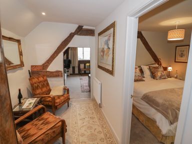 A hallway with two chairs and a side table leading to a living area and a bedroom at The Bindery in Broadway