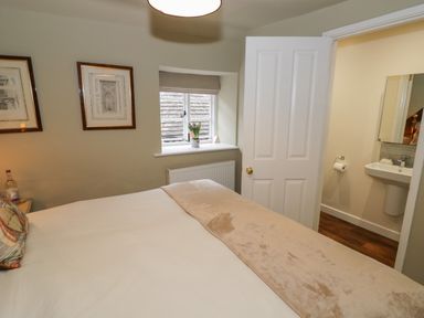 A bedroom with a bed near a window and an open door leading to a bathroom at The Bindery in Broadway