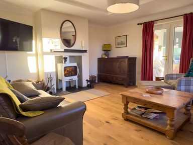 A living room with a leather sofa and a wood-burning stove at Crogal Farmhouse in New Quay