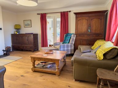 A living room with wooden furniture and red curtains at Crogal Farmhouse in New Quay