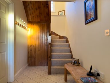 A hallway with carpeted stairs wooden bench and coat hooks at Crogal Farmhouse in New Quay