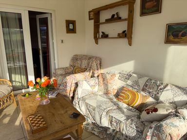 A living room with floral sofas a wooden coffee table with flowers and a wicker chair at Crogal Farmhouse in New Quay