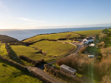 A coastal farmland area with green fields a house and a road near the sea at Sea the Stars in New Quay