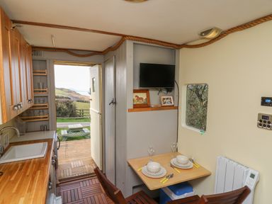 A kitchen and dining area with wooden cabinets and table set for two at Sea the Stars in New Quay