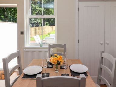 A dining table set with plates wine glasses and a vase of yellow roses in a room with a window and white doors at 2 Twizel Station Cottage in Cornhill-on-Tweed near Norham