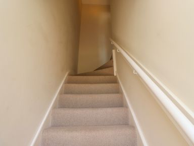 A carpeted staircase with beige walls and a white handrail at 2 Twizel Station Cottage Cornhill-on-Tweed near Norham
