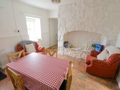 A dining room with a red checkered tablecloth on the table two orange armchairs and a white stone fireplace at Marys Cottage Theur near Riverstown County Sligo
