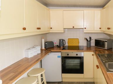 A kitchen with cream cabinets a wooden countertop white canisters and appliances at Marys Cottage Theur near Riverstown County Sligo
