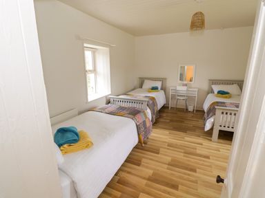 A bedroom with three single beds a window a small desk with a chair and a mirror on the wall at Marys Cottage Theur near Riverstown County Sligo