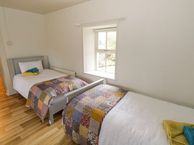 A bedroom with two single beds and a window at Marys Cottage Theur near Riverstown County Sligo