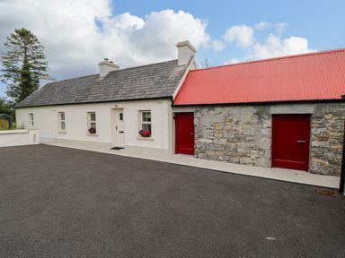 A cottage with white walls and a stone extension with red doors and red roof at Mary's Cottage in Theur near Riverstown County Sligo