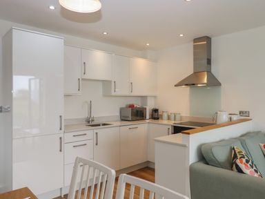 A kitchen with white cabinets a microwave coffee machine and a stainless steel extractor hood at 5 Ocean Reach in Bolberry