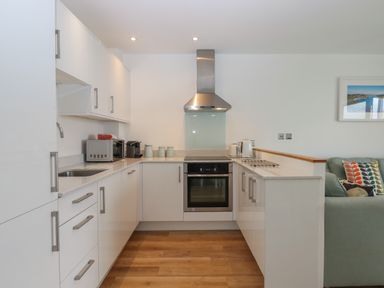A kitchen with white cabinets a stainless steel oven and hood a microwave kettle and coffee machine at 5 Ocean Reach in Bolberry