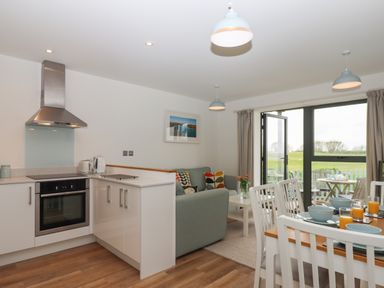 A kitchen area with white cabinets and stainless steel oven next to a dining table with blue dishes and orange drinks at 5 Ocean Reach in Bolberry