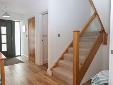 An entryway with a carpeted staircase and wooden doors at 5 Ocean Reach in Bolberry
