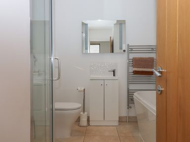 A bathroom with a toilet sink cabinet mirror towel on rack and bathtub at 5 Ocean Reach in Bolberry