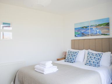 A bedroom with a bed with folded towels and blue patterned pillows at 5 Ocean Reach in Bolberry
